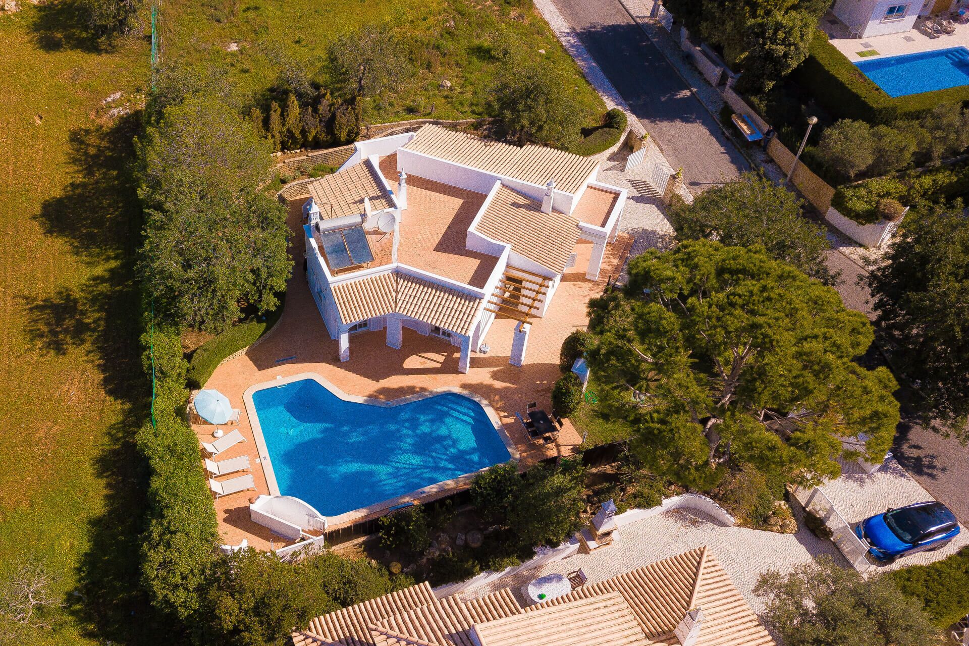 An aerial view of a property with a swimming pool, outdoor seating, and a landscaped garden.