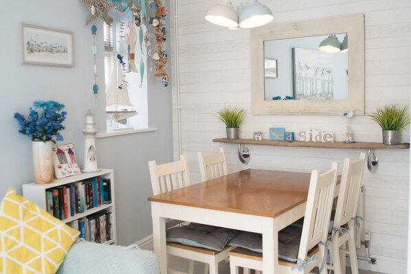 Un coin repas avec une table et des chaises en bois, une bibliothèque, un miroir et des objets décoratifs accrochés au mur.
