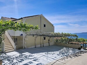 Un bâtiment doté d’un escalier, d’une pergola couverte de plantes grimpantes et offrant une vue sur la mer.