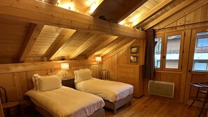 A cozy attic bedroom with two beds, wooden walls, and a sloped ceiling. - Superb chalet: 50m to ski lift. 6 large bedrooms, sleeps 12, sauna & steam rooms (Saint-Jean-D'aulps)