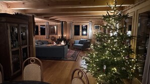 A cozy living room with a fireplace, a Christmas tree, and a dining area with wicker chairs. - Superb chalet: 50m to ski lift. 6 large bedrooms, sleeps 12, sauna & steam rooms (Saint-Jean-D'aulps)