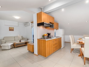 Un espacio habitable compacto con kitchenette, comedor y zona de estar.