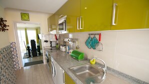 Une cuisine avec des meubles de couleur jaune, un évier en acier inoxydable et un four à micro-ondes.