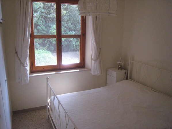 A bedroom with a single bed, a nightstand, a window with curtains, and a view of trees outside. - Villa plus Annex with Private Pool (BETTONA)