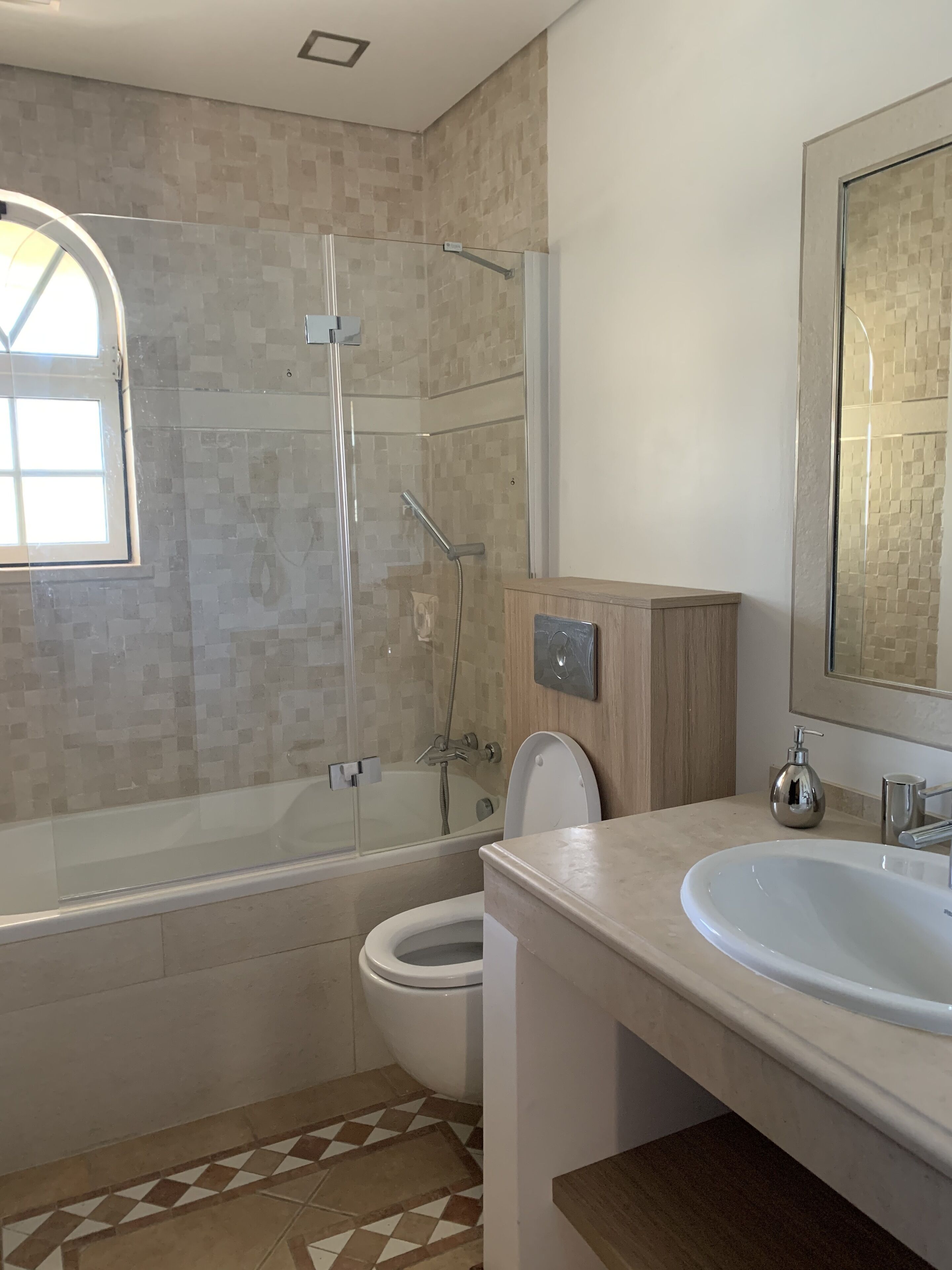 Un baño moderno con ducha de vidrio, inodoro y lavabo con espejo.