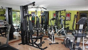 Une salle de sport équipée de divers appareils d’exercice, notamment des tapis de course, des appareils de musculation et un vélo d’appartement.