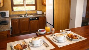 A breakfast setting with croissants, coffee, and orange juice on a wooden table in a kitchen with wooden cabinets and a window. - Fantastic villa with completely private pool, with high wall. Free wifi (Playa blanca)
