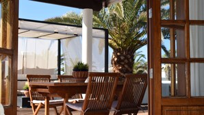 An outdoor patio with wooden furniture, a palm tree, and a covered area with a white canopy. - Fantastic villa with completely private pool, with high wall. Free wifi (Playa blanca)
