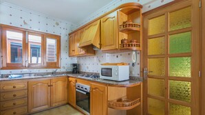 Une cuisine avec des meubles de rangement en bois, un four à micro-ondes, une cuisinière et un évier.