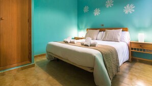 Une chambre d’hôtel avec un lit, une armoire en bois et un mur de couleur turquoise orné de motifs floraux décoratifs.