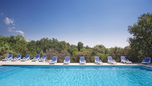 Ein Swimmingpool mit blauen und weißen Liegestühlen, die am Rand aufgereiht sind.