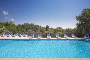 Ein Swimmingpool mit blauen und weißen Liegestühlen, die am Rand aufgereiht sind.