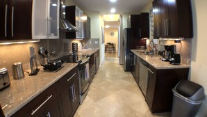 A modern kitchen with dark cabinets, stainless steel appliances, and a granite countertop. - 3BR Home wRooftop by Ideal Experience VR (Fort Lauderdale)