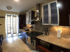 A modern kitchen with dark cabinetry, stainless steel appliances, and a granite countertop.
