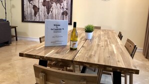 A wooden dining table with a sign, a bottle of wine, and a small plant. - 3BR Home wRooftop by Ideal Experience VR (Fort Lauderdale)