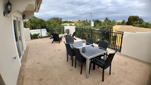 A patio with a table and chairs, a small garden, and a view of the cityscape. - 3BR Home wRooftop by Ideal Experience VR (Fort Lauderdale)