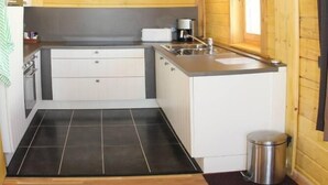 A compact kitchen with wooden walls, a central island, and a small trash bin. - Chalet - Montgellafrey (Montgellafrey)