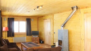 A log cabin interior with a sofa set, a fireplace, a television, and a ceiling light fixture. - Chalet - Montgellafrey (Montgellafrey)