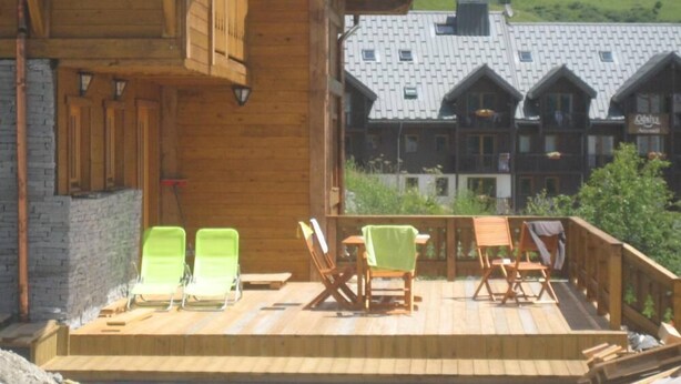 A wooden deck with outdoor seating and a view of a mountain village. - Chalet - Montgellafrey (Montgellafrey)