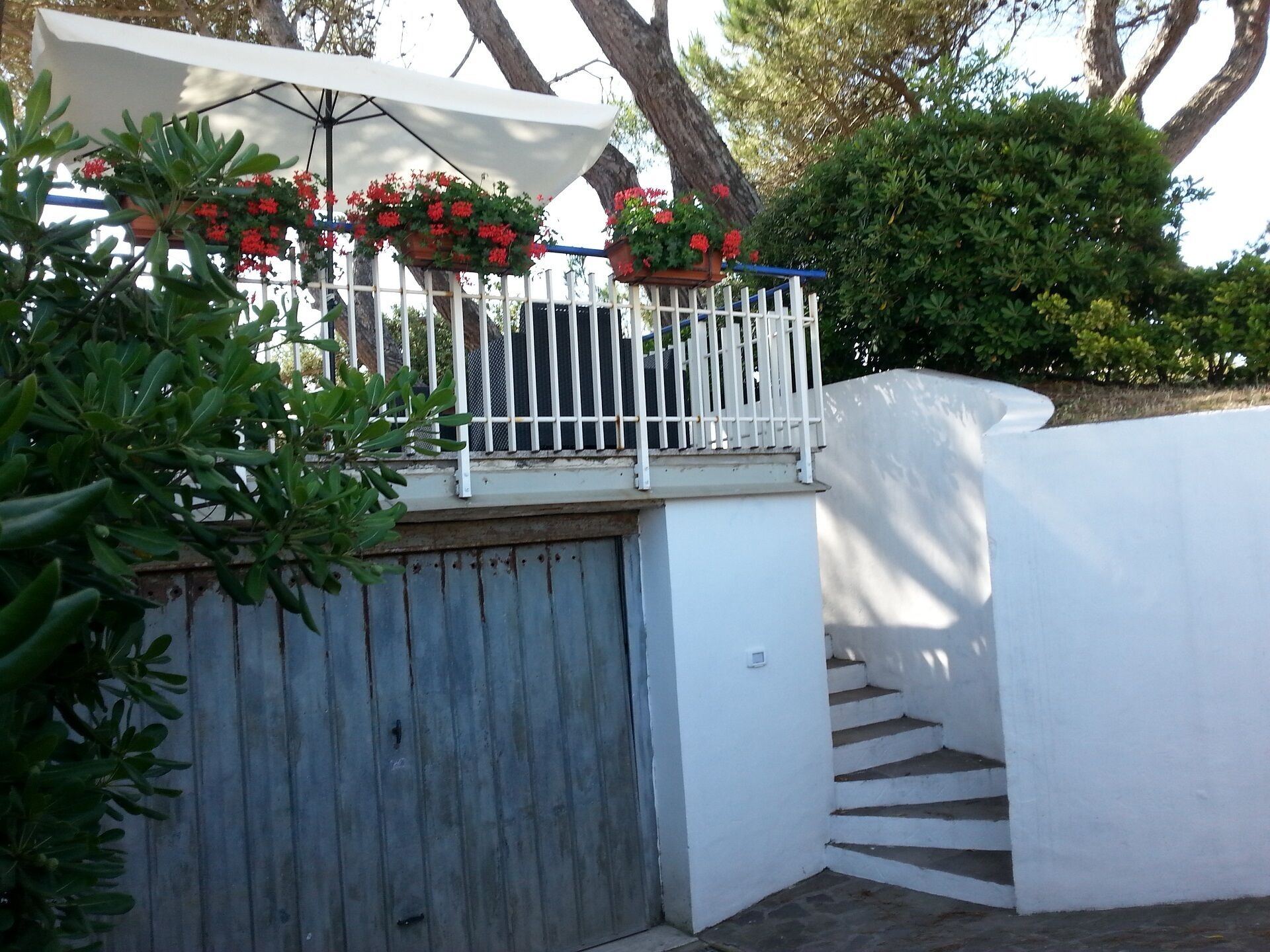 A white outdoor area with a metal gate, a white fence, and a staircase leading up.