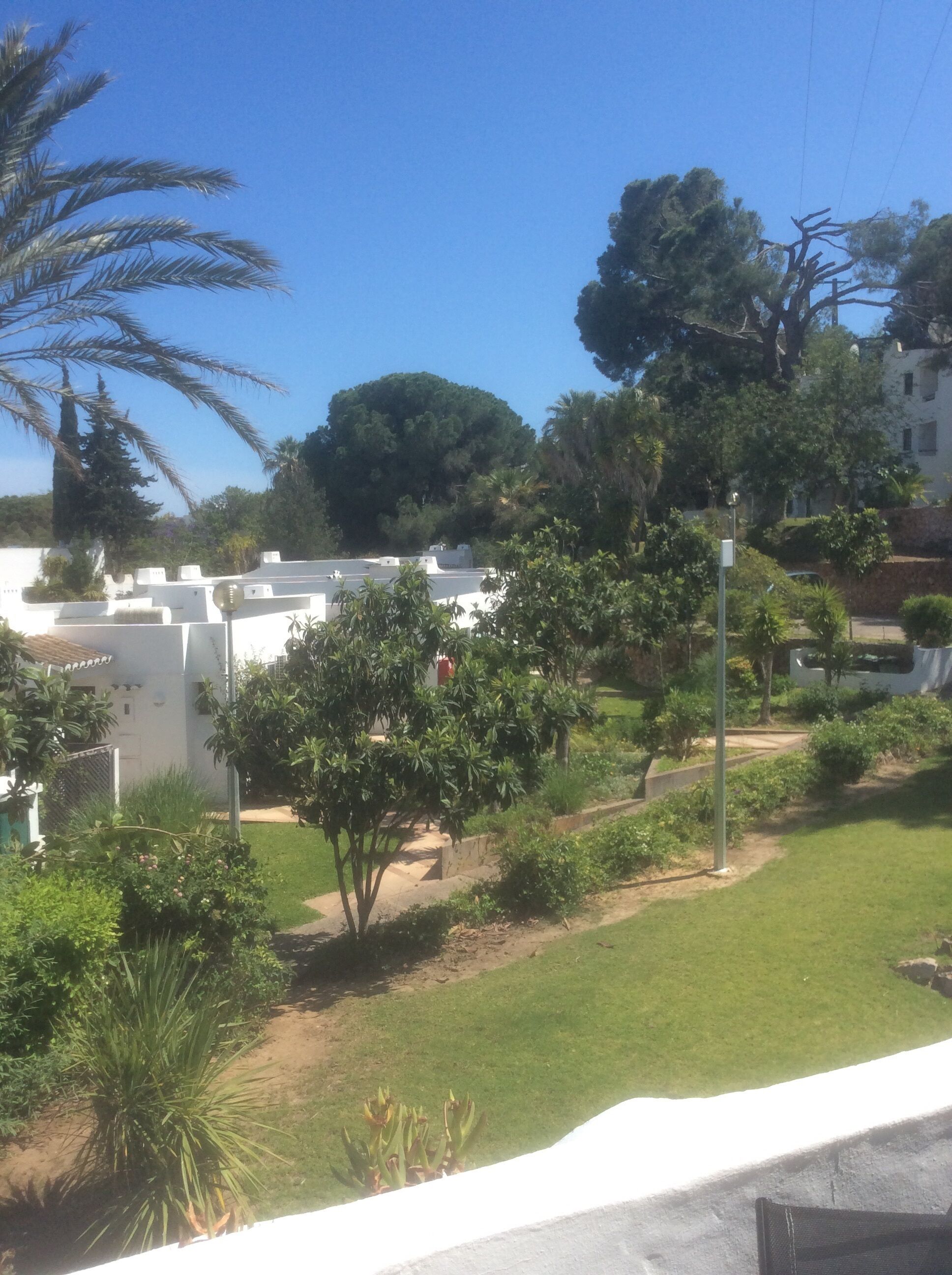 A residential area with white buildings, green lawns, and trees.