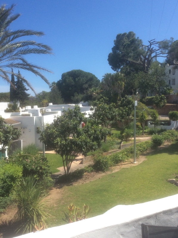 A residential area with white buildings, green lawns, and trees.