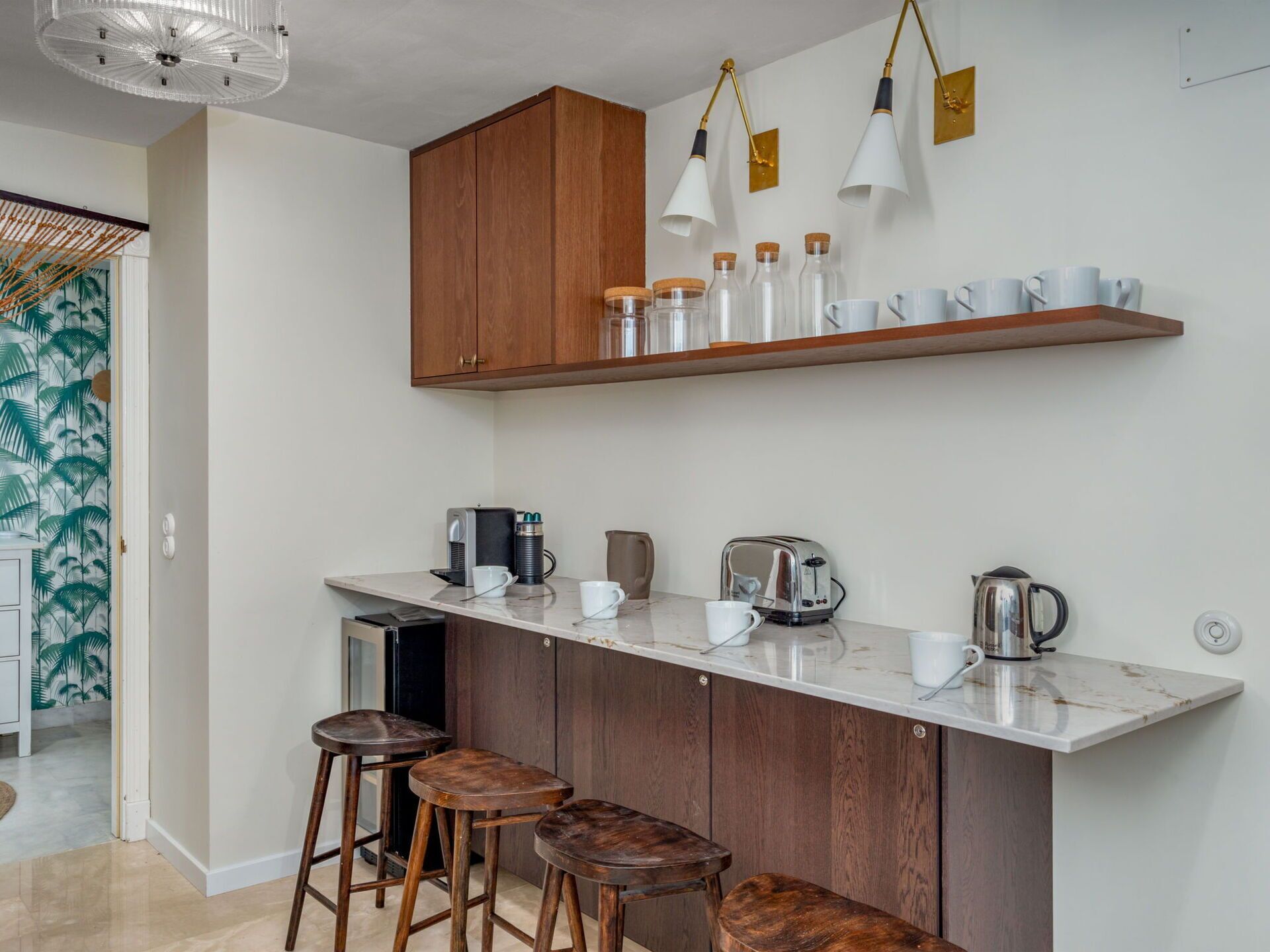 Een moderne keuken met een marmeren aanrechtblad, houten kastjes en barstoelen.