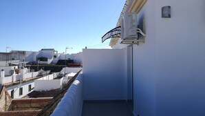 Un toit surmonté d’un bâtiment blanc, d’une cheminée et d’une antenne parabolique.