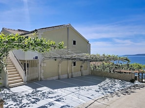 A building with a staircase, a pergola with vines, and a view of the sea. - Cosy apartment for 4 people with WIFI, A/C, pool, TV and terrace (Solin)