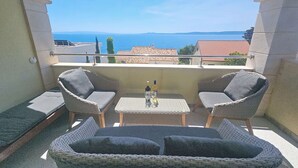A balcony with wicker furniture, a table, and a bottle.