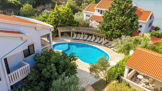 A pool area with a circular pool, lounge chairs, and a pergola.