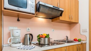 Cucina con mobili in legno, forno a microonde, macchina del caffè, bollitore, piano cottura a gas e lavandino.