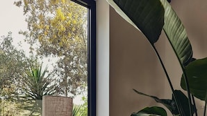 A cozy seating area with a cushioned sofa, a lamp, and a large plant by a window. - Sunny side Beach house (Vela Luka)