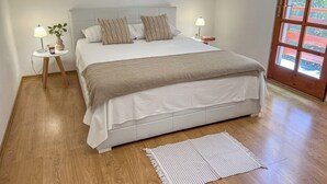 A neatly arranged bedroom with a large bed, bedside tables with lamps, a small plant, and a view through a window. - Sunny side Beach house (Vela Luka)