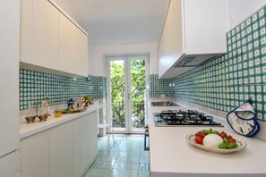 A kitchen with white cabinets, green checkered backsplash, and a gas stove. - Villa Aglaia Moorish Luxury with Panoramic Sea Views (Casamicciola Terme)