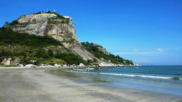Uma praia com penhascos rochosos e céu azul límpido.