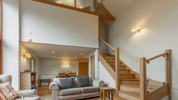 A spacious living area with a staircase, a sofa, and a dining table. - Palgrave Barn, Burnham Market, Norfolk (Burnham Market)