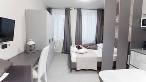 Une chambre d’hôtel avec un lit, un bureau, une télévision et une fenêtre avec des rideaux.
