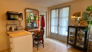 A compact kitchen with a microwave, a small refrigerator, and a wooden dining table with chairs.