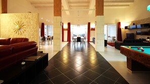 Amplia sala de estar con mesa de billar, sofá de cuero y comedor con sillas y mesa.