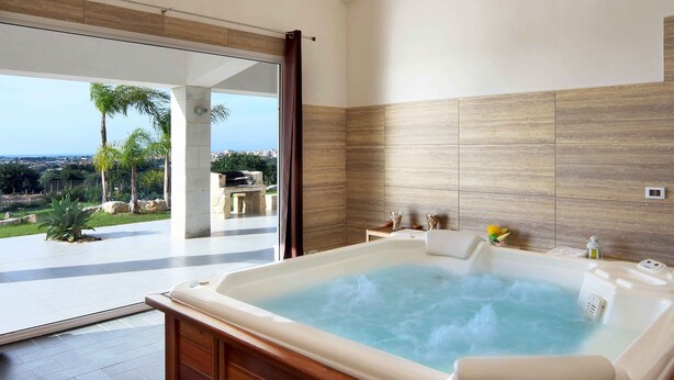Un baño moderno con una bañera grande, vistas al exterior y una pared de piedra.