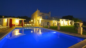 Una casa moderna con piscina, mobiliario exterior e iluminación cuidada.