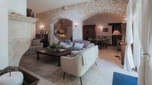 A cozy living room with a stone archway, a fireplace, a coffee table, and a sofa. - Charm Attitude building with swimming pool 5 * very close Beaune (Meursanges)