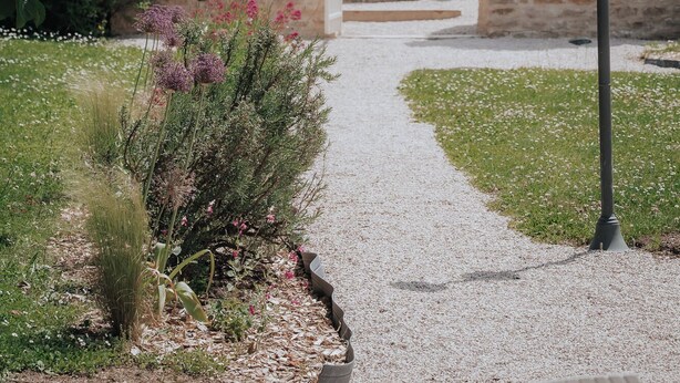 A pathway leading to a stone structure with a tiled roof, surrounded by greenery and a gravel path. - Charm Attitude building with swimming pool 5 * very close Beaune (Meursanges)