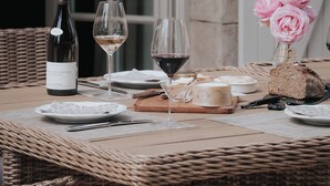 A dining table set with a bottle of wine, two glasses, a plate, a jar, and a loaf of bread. - Charm Attitude building with swimming pool 5 * very close Beaune (Meursanges)