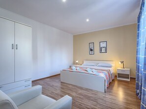 A bedroom with a bed, bedside tables, a wardrobe, and a chair. - Cosy apartment for 4 people with pool, A/C, WIFI, TV and terrace (Umag)