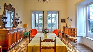 Comedor con mesa lista para dos, una araña y vistas a través de las ventanas.