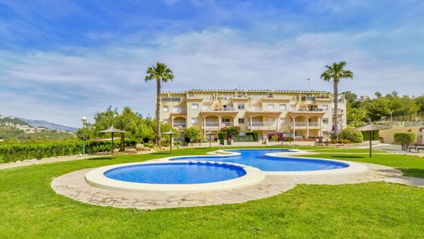 Un hotel con zona de piscina, palmeras y vistas del paisaje circundante.