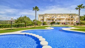 Una piscina con escalones circulares que conducen al borde, rodeada de un césped cuidado y palmeras.