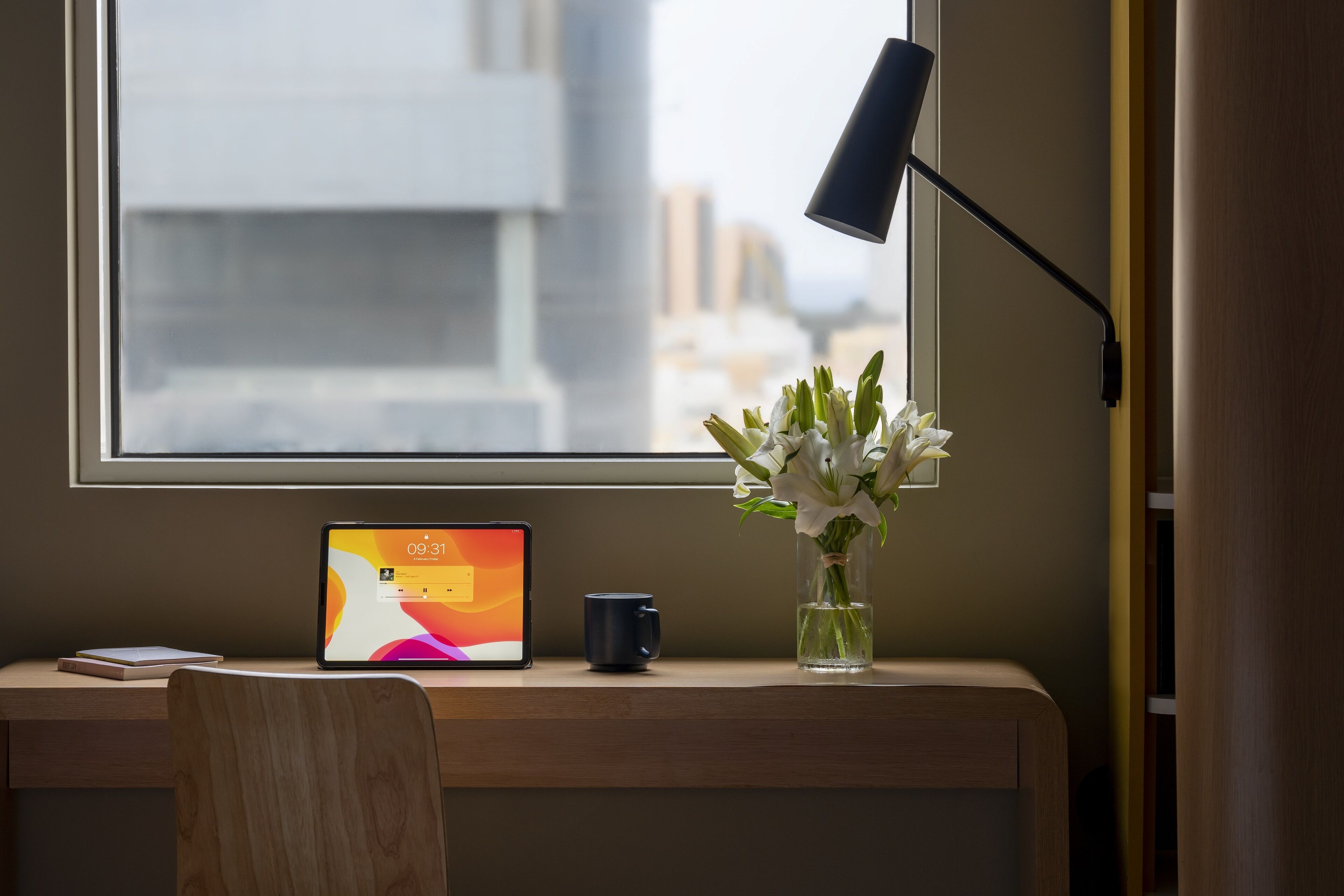 A desk with a laptop, a mug, and a vase with flowers.